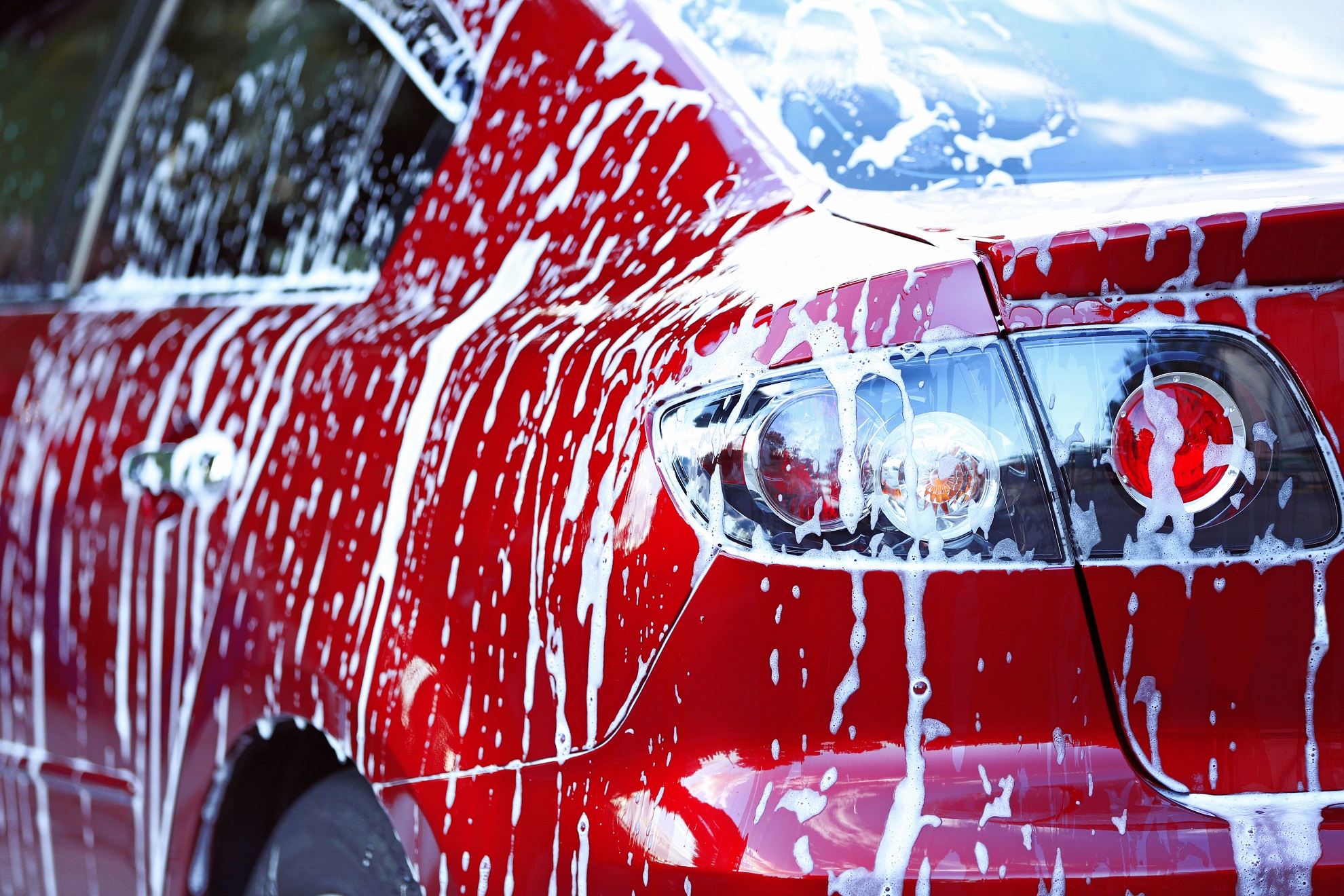 Car washing concept. Red car in foam